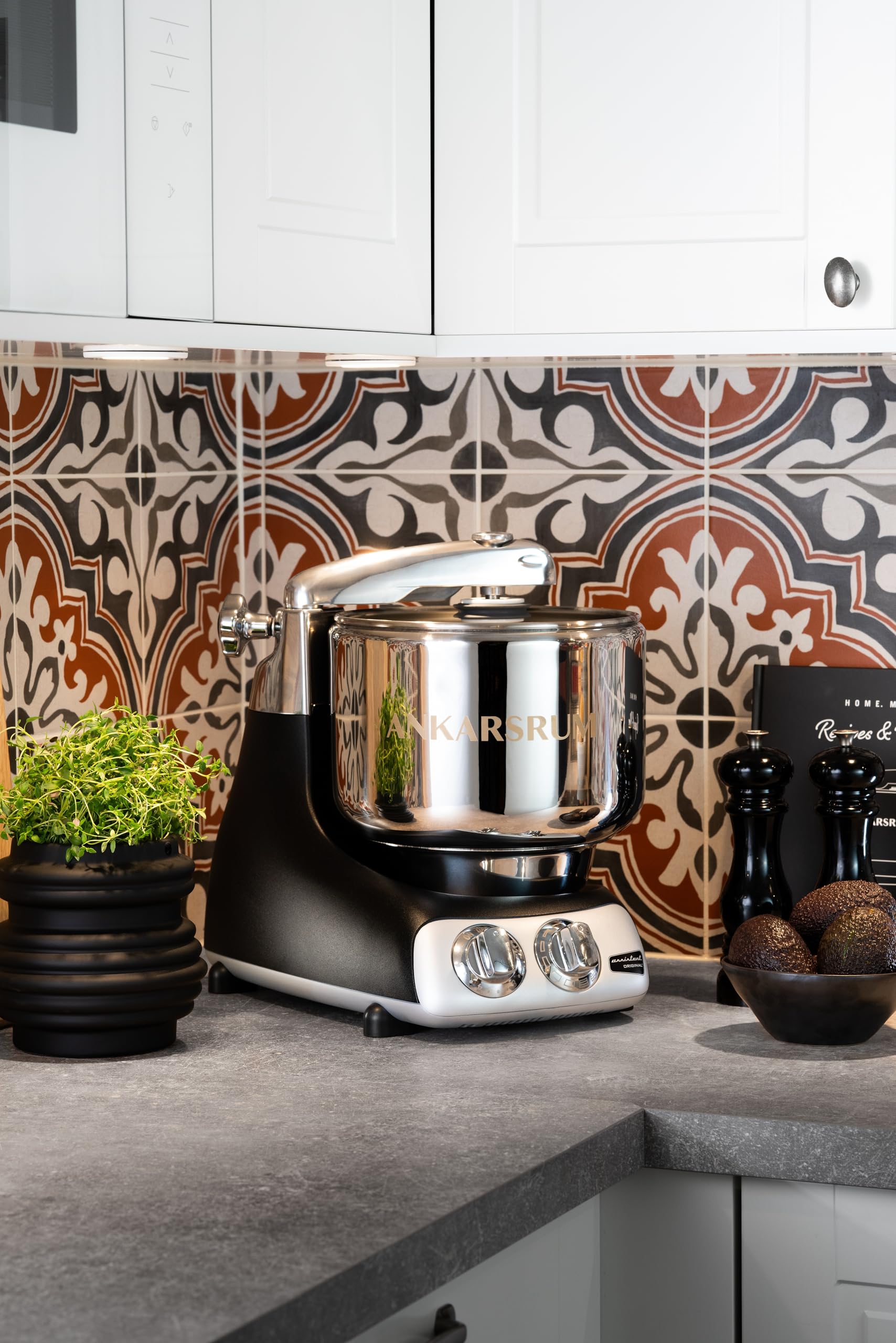 Black Kitchen mixer on a countertop with decorative tiles and kitchen items in the background