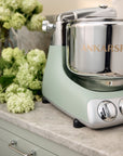 Nordic sage standing mixer with 'Ankarsrum' branding on a countertop with flowers in the background