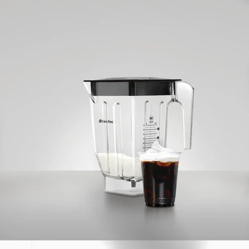 Blender container with a glass of brown liquid with foam on top on a gray background