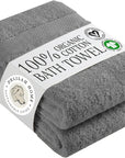 A stack of two folded gray cotton bath towels wrapped with a white paper label that reads '100% Organic Bath Towel' and shows the Delilah Home brand logo.