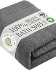 A folded dark gray cotton bath sheet wrapped with a white paper band label that reads '100% Organic Cotton Bath Sheet' and shows the Delilah Home brand logo.