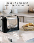 Dualit toaster on a kitchen counter with toast and kitchen items such as a sandwich cage in the background