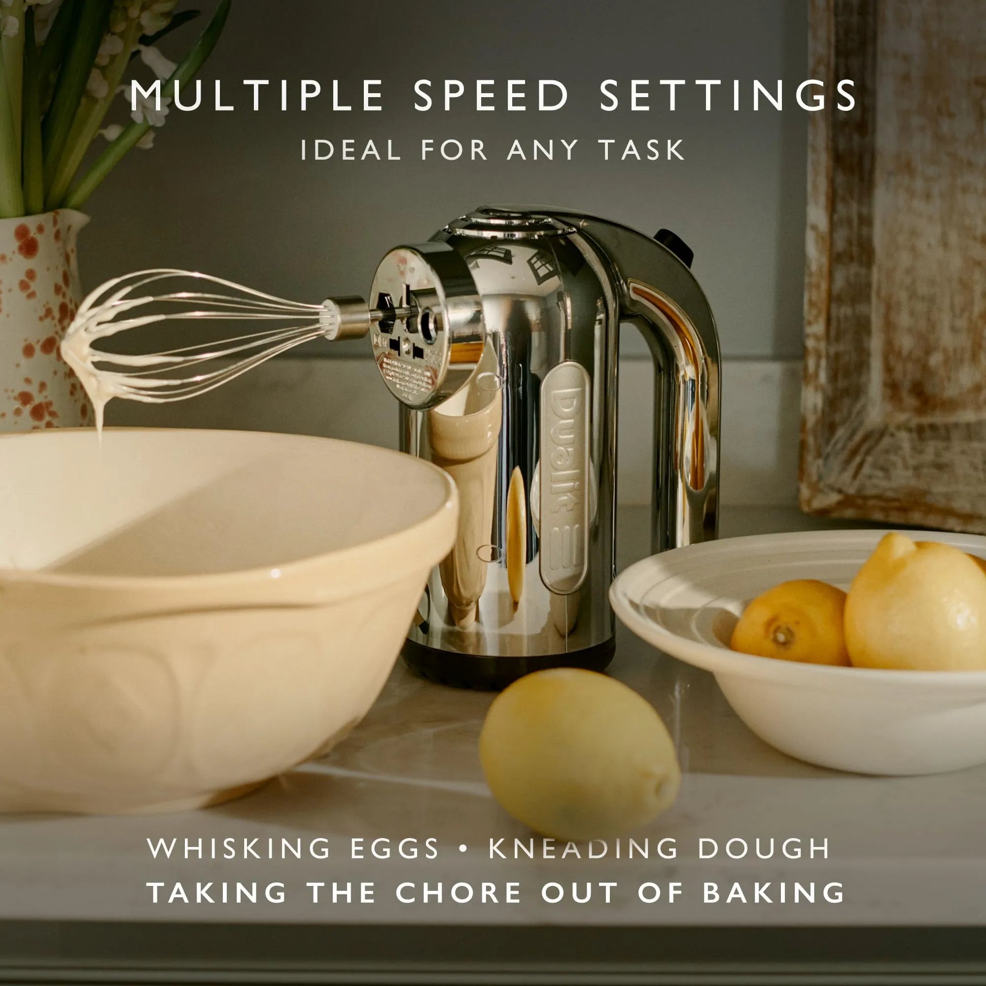 Dualit hand mixer next to a bowl with text "Multiple Speed Settings Ideal for Any Task" in a kitchen setting