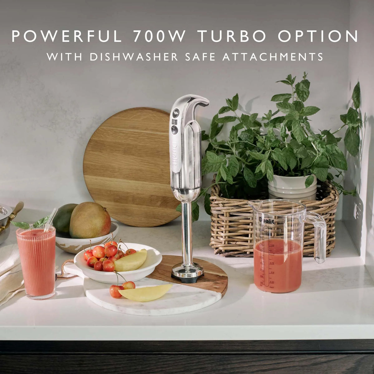 Kitchen scene with a blender on a counter, fruits, and a plant with "Powerful 700W Turbo Option with Dishwasher Safe Attachments" text.
