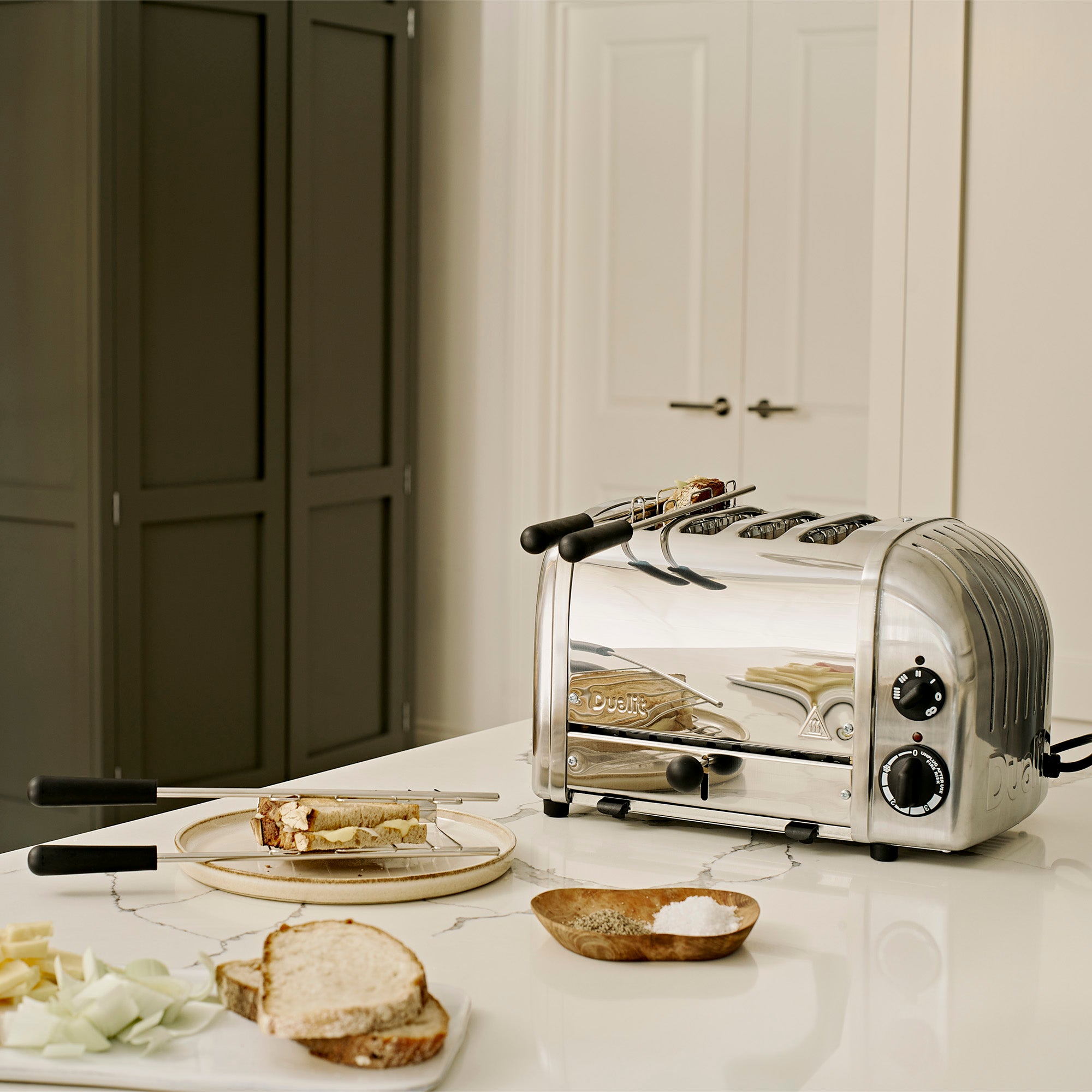 Silver toaster on a kitchen counter with bread and butter