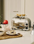 Silver toaster on a kitchen counter with a plate of food, coffee, and a plant.