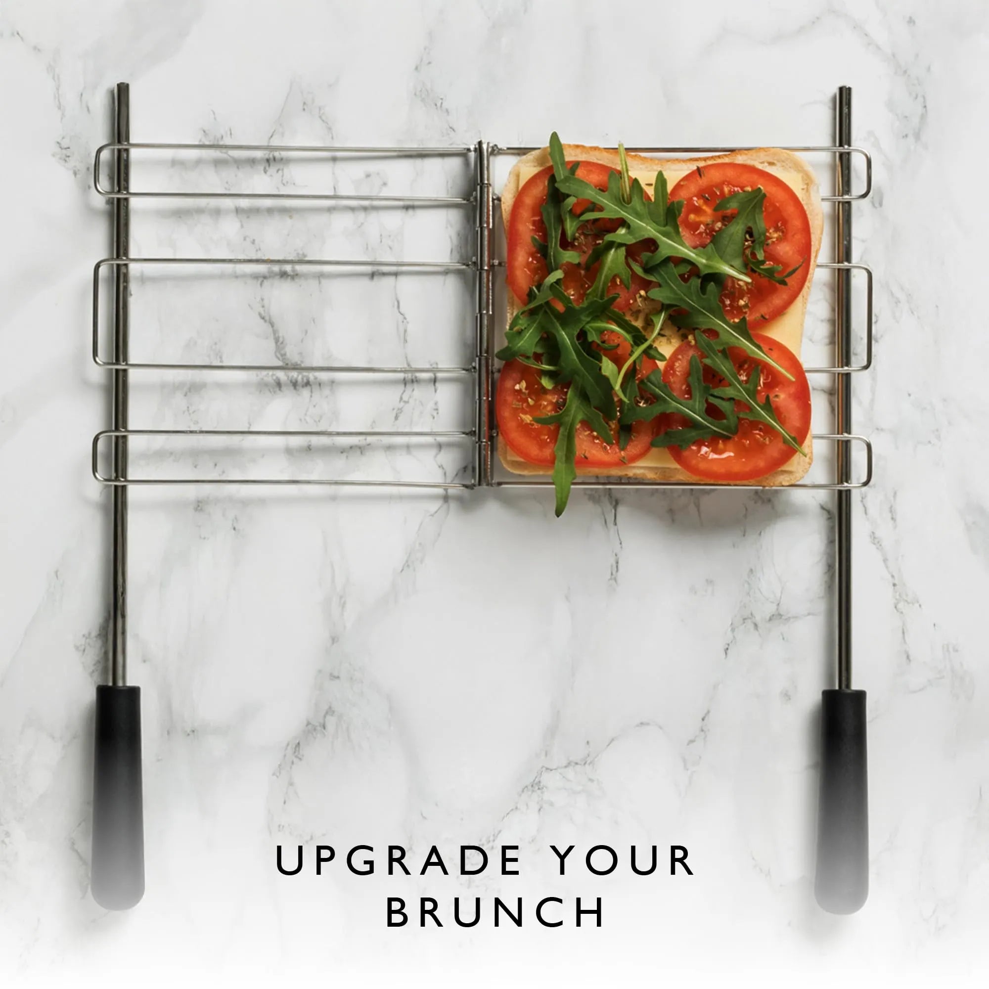 A metal sandwich cage holding a sliced bread with sliced tomatoes and green arugula on top on a white marble surface, with the text 'UPGRADE YOUR BRUNCH' below.