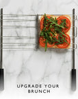 A metal sandwich cage holding a sliced bread with sliced tomatoes and green arugula on top on a white marble surface, with the text 'UPGRADE YOUR BRUNCH' below.