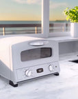 Modern white toaster oven on a kitchen counter with a view of the ocean.