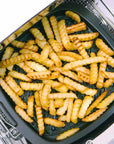 Fried crinkle-cut French fries in a black frying pan in a toaster oven