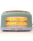 A retro-style two-slot toaster in sage green and light gray, shown with bread inside and the heating elements glowing bright orange. The toaster features a round silver dial on the front and a small side handle.