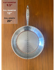Stainless steel frying pan on a wooden surface with measurements displayed.