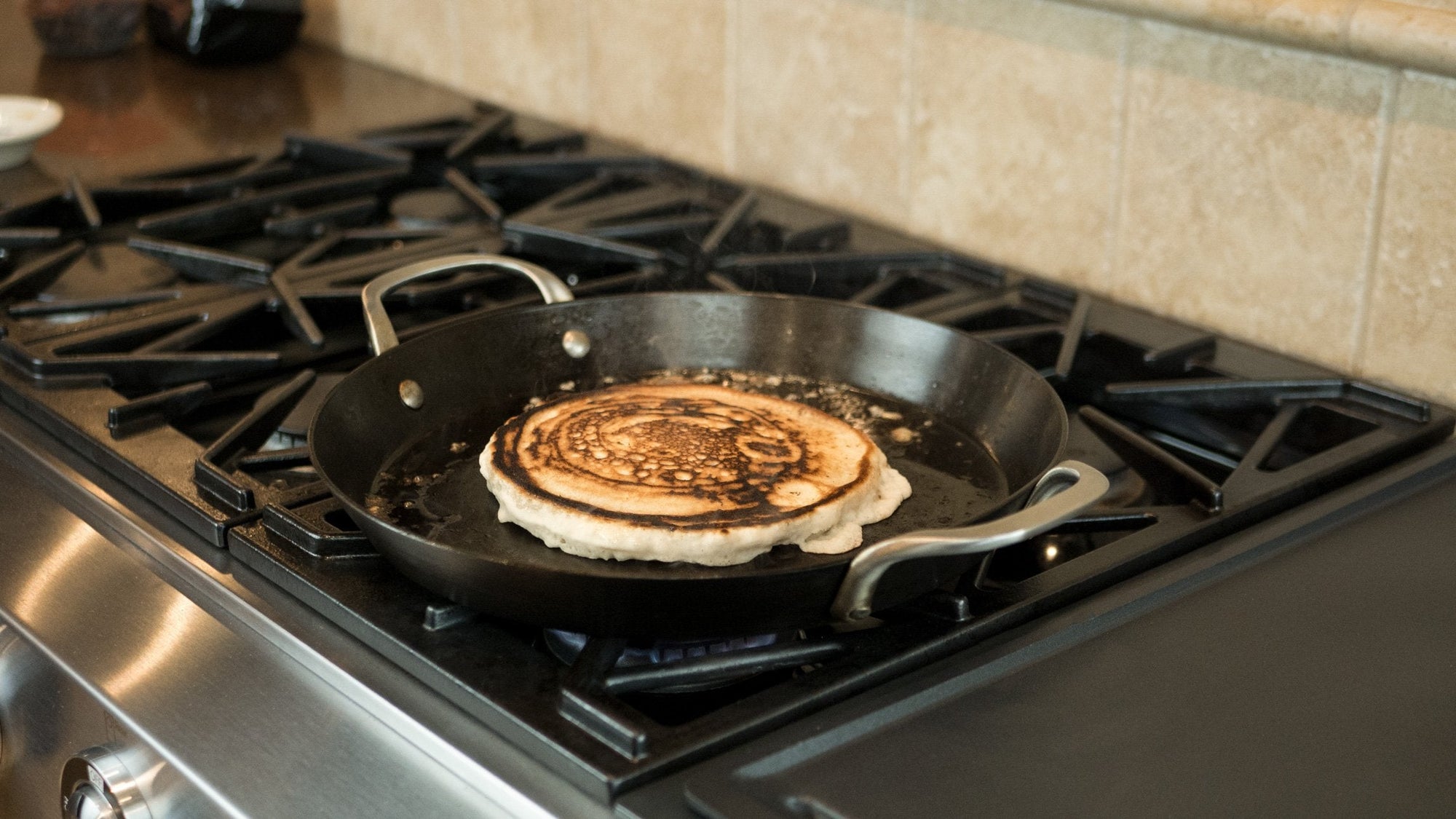 Pan on a stove with a tortilla cooking inside