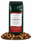 1 lb Decaf Holiday Blend coffee beans bag with coffee beans, hazelnuts, and cinnamon sticks in front displayed on a white background