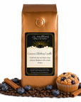 1 lb Cinnamon Blueberry Crumble coffee beans bag with coffee beans, blueberries, cinnamon sticks, and blueberry crumble muffin in front displayed on a white background