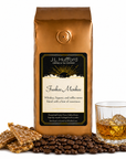 1 lb Funkee Monkee coffee beans bag with coffee beans, toffee bark, and a glass of whiskey in front displayed on a white background