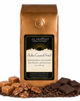 1 lb J.L. Hufford Praline Caramel Swirl Coffee with coffee beans, roasted pralines, caramel blocks, and dark chocolate bars in front displayed on a white background