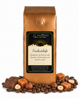 1 lb J.L. Hufford Snickerdelight coffee bag with coffee beans, milk chocolate bar, hazelnuts, and blocks of caramel on a white background
