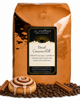5 lb Decaf Cinnamon Roll coffee beans bag with coffee beans, cinnamon sticks, and cinnamon roll in front displayed on a white background