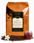 5 lb J.L. Hufford Decaf Raspberry Cream coffee bag with coffee beans, vanilla sticks, and a jar of raspberry jam on a white background