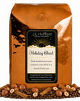 5 lb Holiday Blend coffee beans bag with coffee beans, hazelnuts, and cinnamon sticks in front displayed on a white background