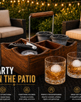 Wooden drink caddy with ice molds and glasses on a patio table.