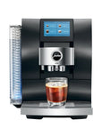 A Jura Z803 automatic coffee machine in black and silver, shown with a glass of iced espresso on its drip tray and a water tank on the left, against a solid white background.