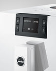 White coffee machine with digital display and control panel on a light gray background