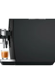 A sleek black coffee machine with a chrome-finished spout and drip tray, shown on a plain white background with a small glass of espresso underneath.