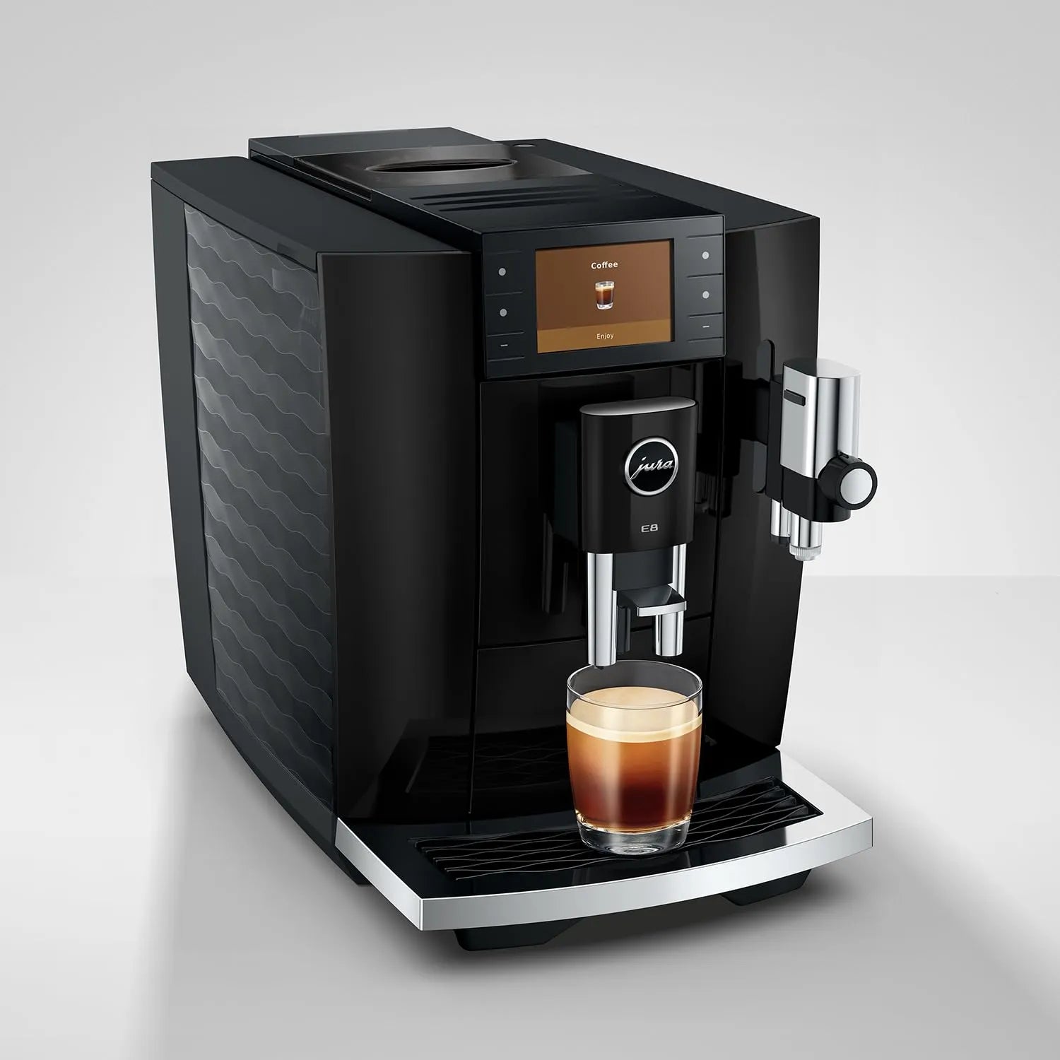 A black Jura coffee machine with a digital display screen, shown dispensing coffee from a glass cup on its drip tray against a light gray background.