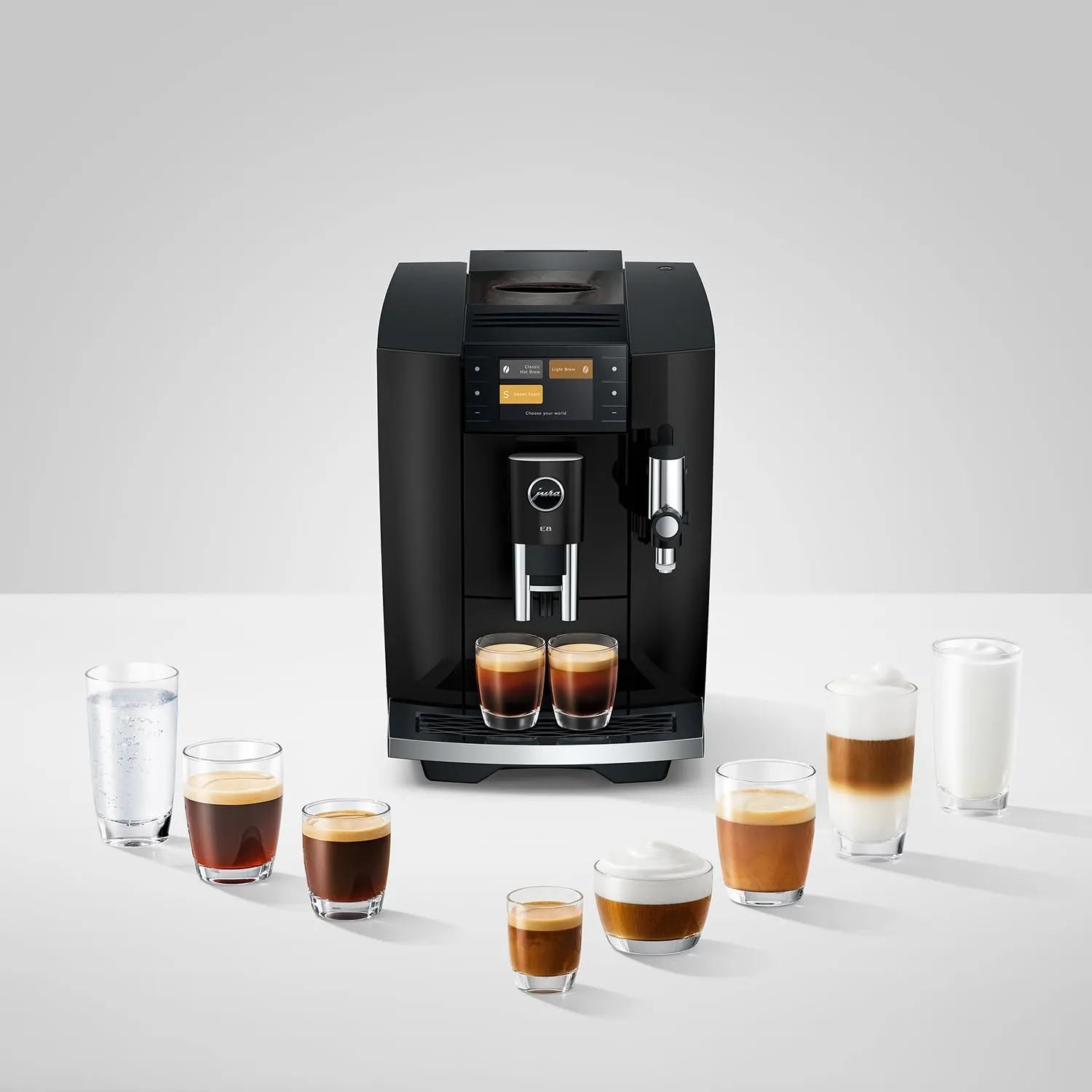 A black Jura coffee machine with two cups of espresso underneath, surrounded by various coffee and milk drinks on a light gray background.