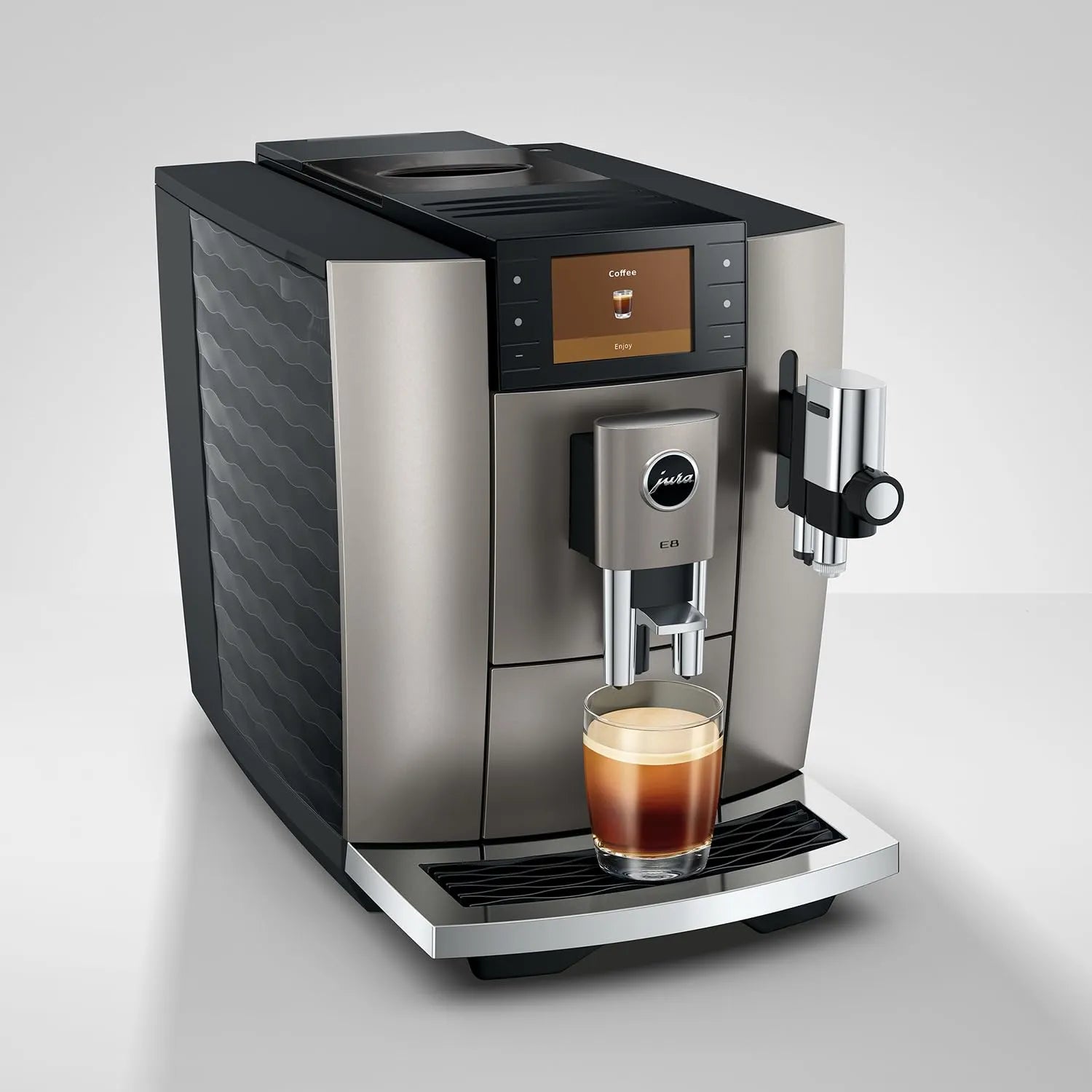 A Jura commercial-style espresso machine in brushed silver and black, shown with a glass of espresso on the drip tray against a light gray studio background.