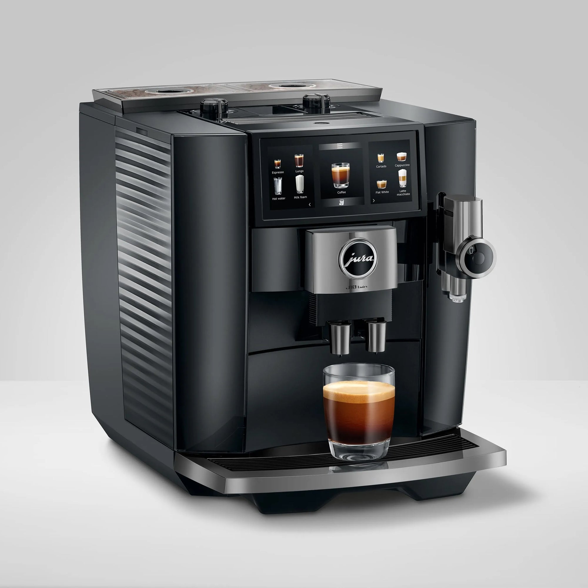 A black and stainless steel Jura coffee machine with a glass of espresso and latte underneath, set against a clean light gray background.