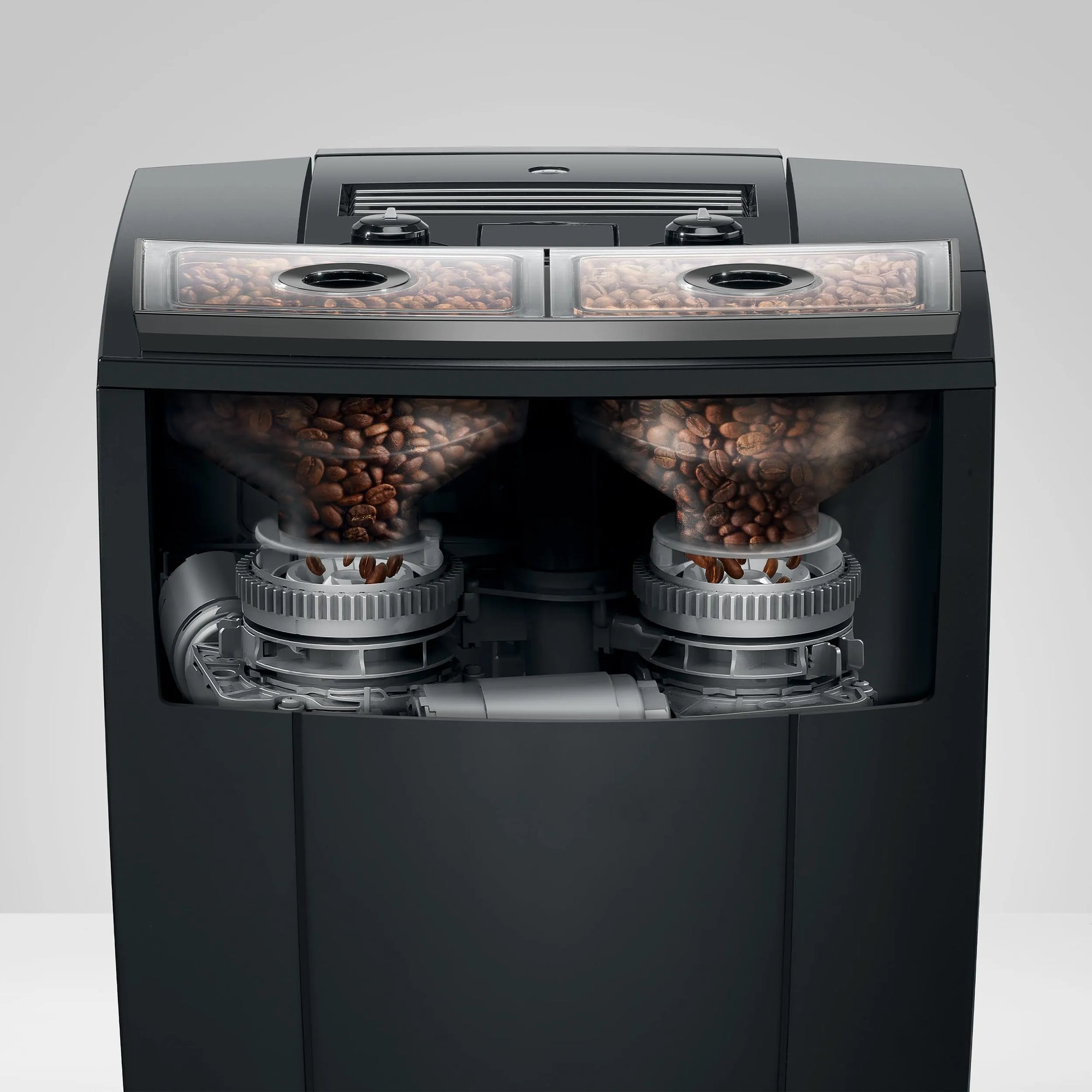A black coffee grinder shown from the front with a transparent view, revealing two transparent bean hoppers filled with coffee beans and silver grinding mechanisms inside.
