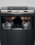 A black coffee grinder shown from the front with a transparent view, revealing two transparent bean hoppers filled with coffee beans and silver grinding mechanisms inside.