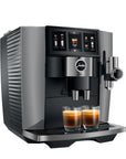 A Jura coffee machine in dark gray and black, shown with two glasses of espresso on its drip tray against a white background.
