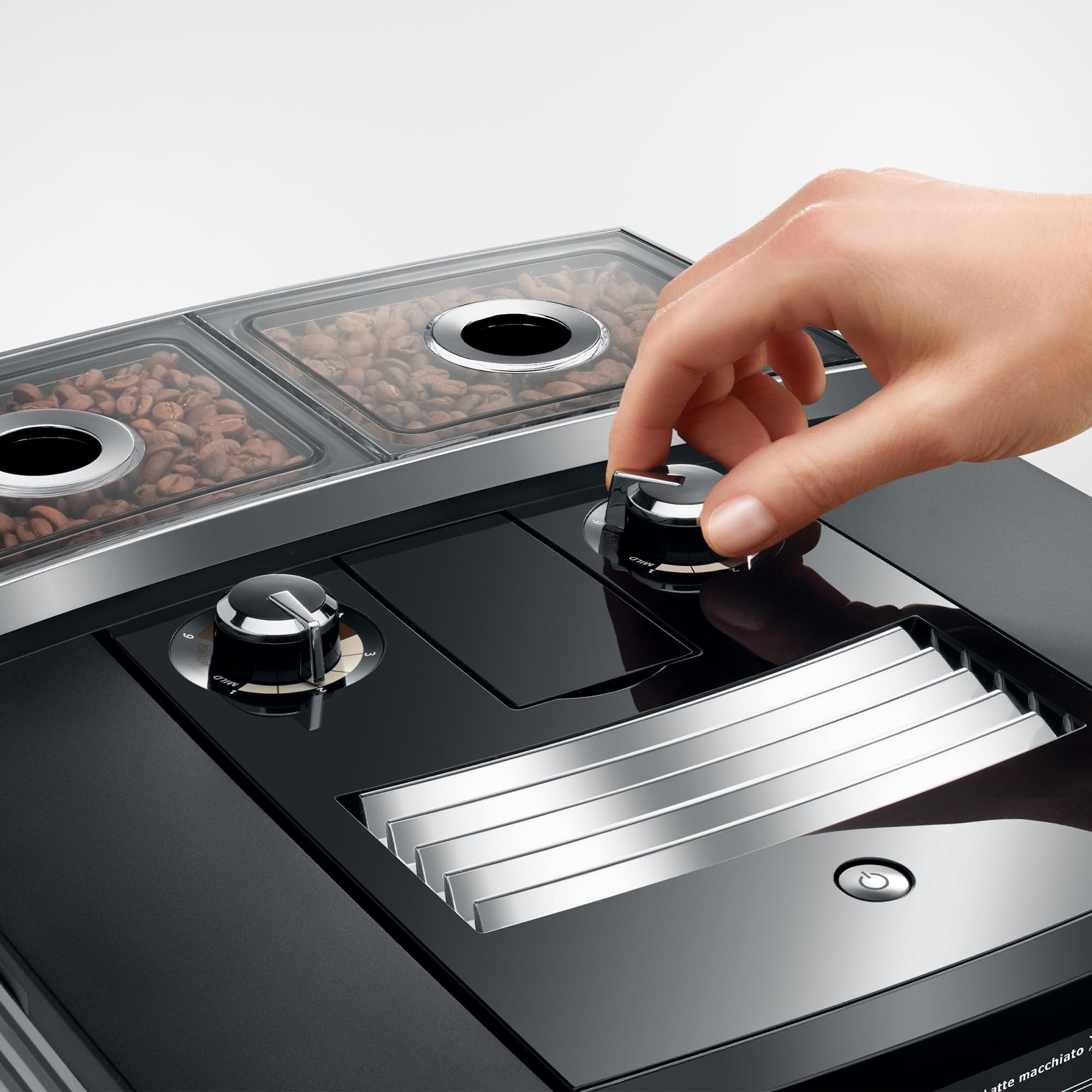 Hand interacting with a modern coffee machine displaying bean compartments.