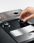 Hand interacting with a modern coffee machine displaying bean compartments.