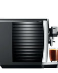 Side view of black and silver coffee machine with a glass of coffee on a white background