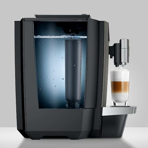 Side view of modern coffee machine with a glass of layered coffee and water filter container on a light gray background