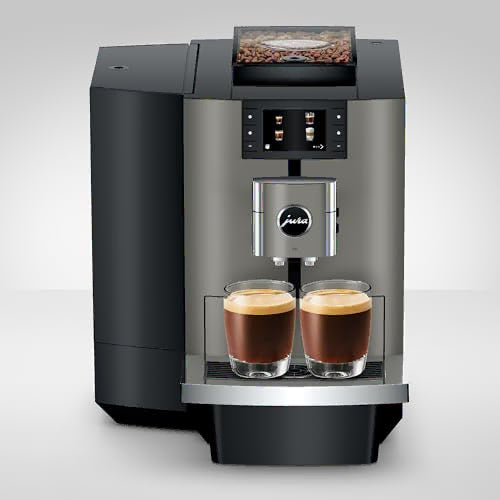A modern automatic coffee machine in black and stainless steel, shown with two glasses of espresso on the drip tray against a light gray studio background.
