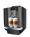 A Jura commercial-style coffee machine in dark gray and black, shown with two tall glasses of layered latte macchiato on the drip tray, against a plain white background.