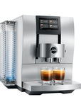 A sleek, stainless steel Jura coffee machine with a digital touch screen, shown with two glasses of espresso on its drip tray against a white background.