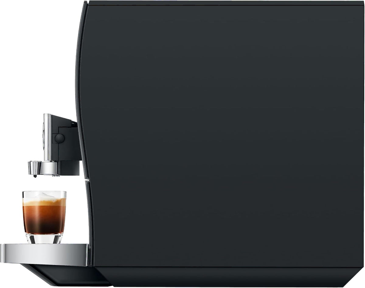 Side view of a sleek black coffee machine with a small glass of espresso on the drip tray, shown against a plain white background.