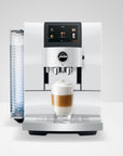 Front view of Diamond White Jura espresso machine with a creamy coffee in glass cup on stand displayed on a white background