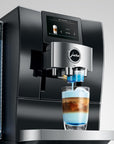 Jura coffee machine dispensing a layered drink into a glass with a clear background