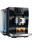 Diamond Black Jura espresso machine with two creamy coffee in glass cup on stand displayed on a white background