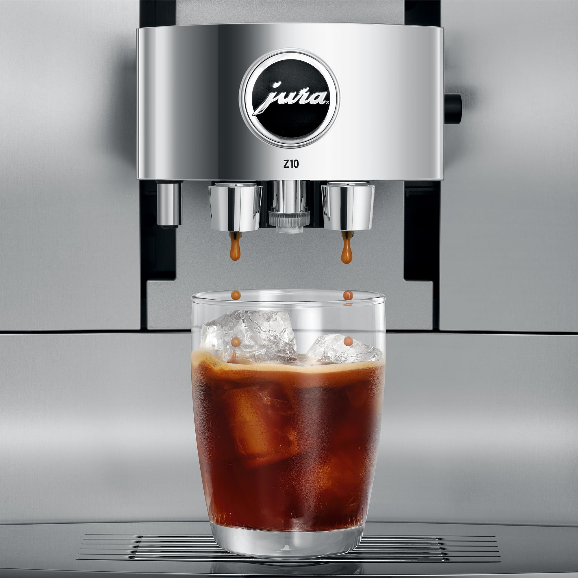 Close up of Aluminum White Jura espresso machine dripping coffee into a glass cup with ice on stand