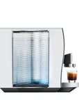 Side view of Aluminum White Jura espresso machine with a creamy coffee in glass cup on stand displayed on a white background