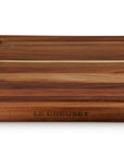 Wooden cutting board with 'Le Creuset' branding on a white background